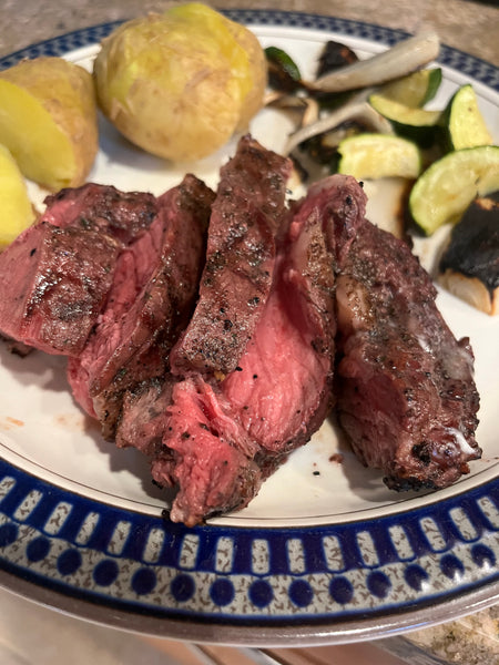 Sliced bison tomahawk steaks on a plate with veggies