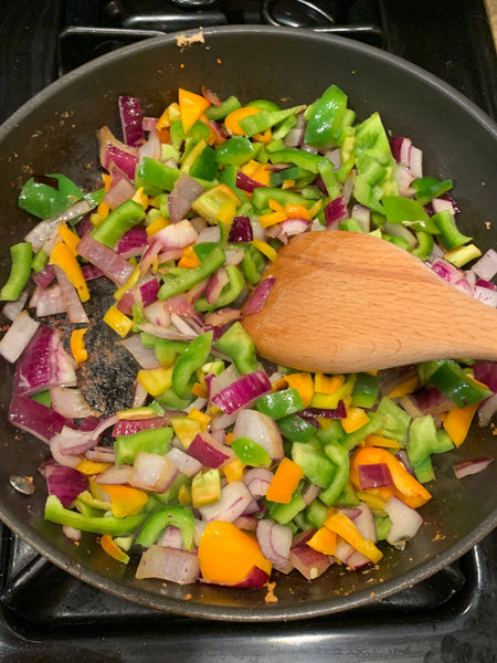 Peppers and onions sautéeing in a skillet