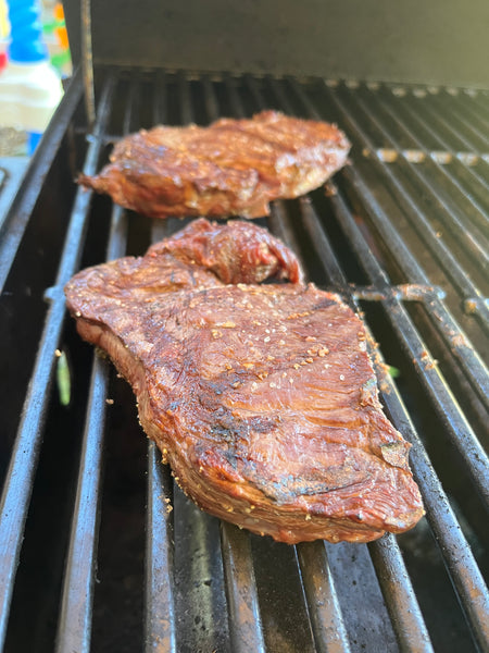 Two elk ribeye steaks on a grill