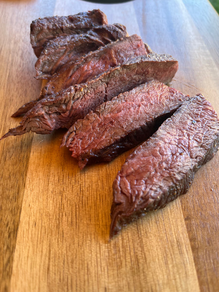Seared and sliced elk ribeye steaks on a wood board