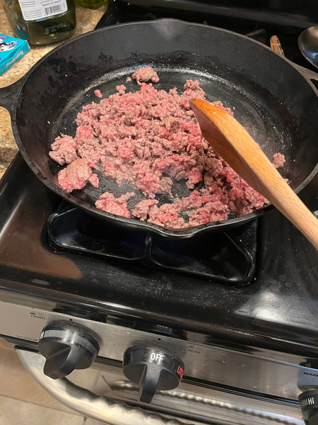Ground elk meat cooking in a cast iron pan