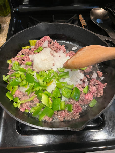 Diced onions and peppers cooking in skillet