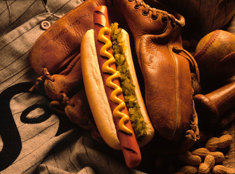 Image of a hot dog with mustard nestled in a baseball glove