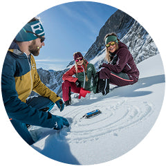 Drei Menschen sitzen im Schnee im Winter. Alpinschule Winterprogramm
