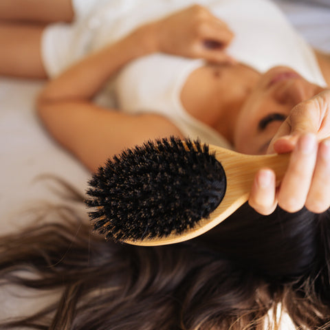 Woman laying with boar bristle hair brush