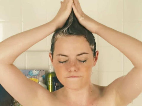 Image of a woman washing her hair in the shower for a healthy and shiny mane.
