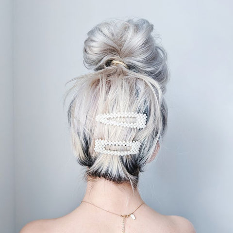 Image of the back of a woman's head with two pearl barrettes