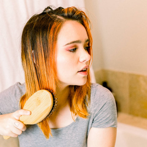 A girl using a boar bristle hair brush to brush her hair