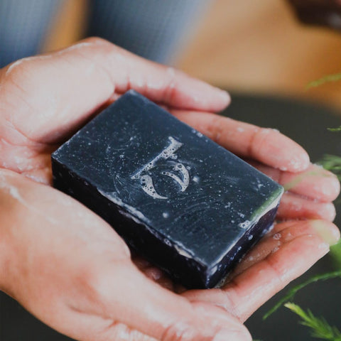 Two hands holding the BBE charcoal bar, a beauty product you didn't know you needed until now.