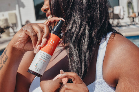 Woman spraying beauty by earth's sea salt texturizing spray in the share citrus breeze in her hair
