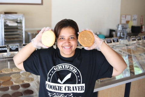 A photo of the founder of Cookie Crave Denton holding 2 cookies