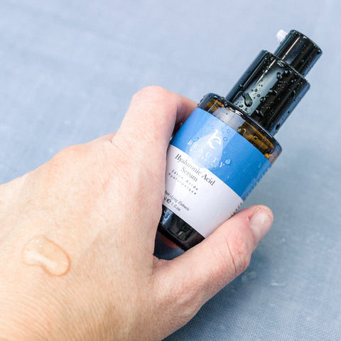 Hand holding beauty by earth hyaluronic acid serum with a swatch on their hand