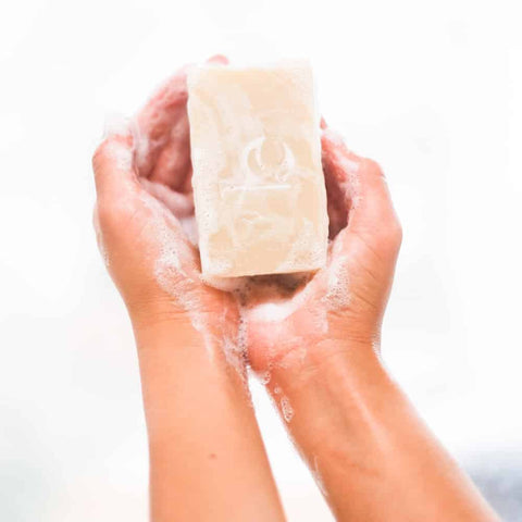 Image of two hands holding a BBE face wash bar full of suds 