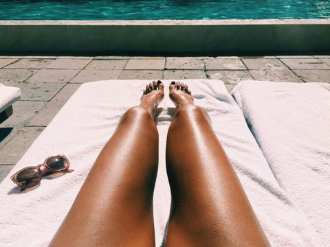 A woman tanning her legs by the poolside