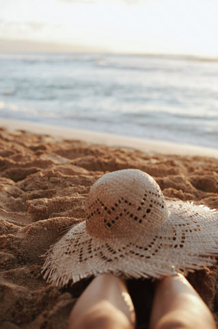 Sun hat resting on legs by the beach