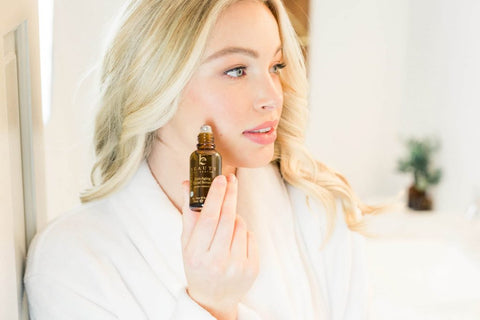 Image of a woman applying the BBE anti-aging serum to her cheek.