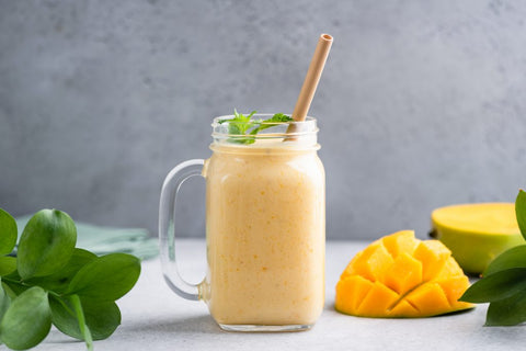 Mango smoothie in glass over grey concrete background. Delicious tropical fruit mango smoothie