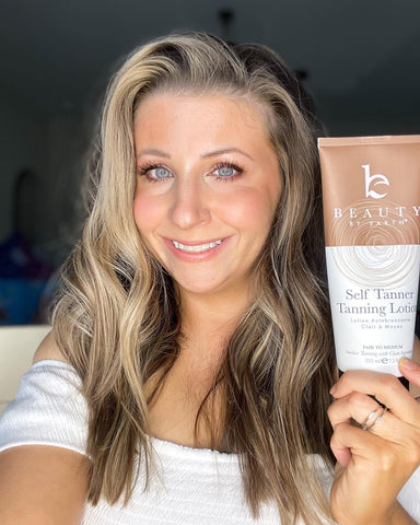 Image of a woman holding her beauty by earth self tanning lotion