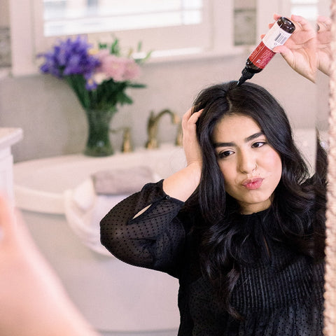 Image of a woman applying the BBE dry shampoo, a back to school essential.