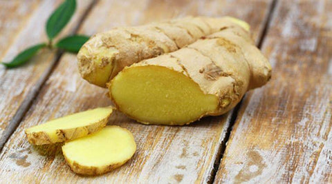 Image of sliced pieces of ginger on a wooden table.