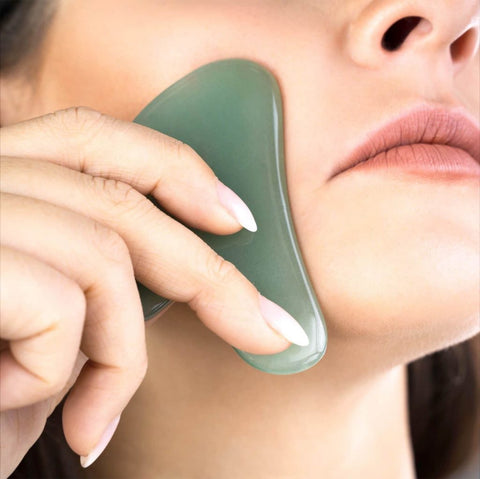 Woman using a jade Gua Sha on her check