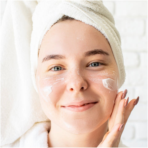 Woman applying moisturizer to her face for dewy skin