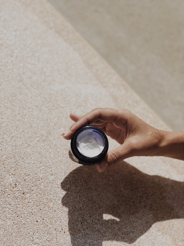 Hand holding a jar of retinol cream