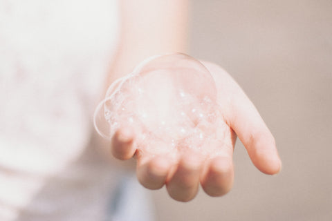 Image of a hand holding shampoo foam. Which, if it has sulfates and parabens, can be bad for your hair. 