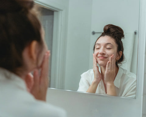Woman washing face in mirror