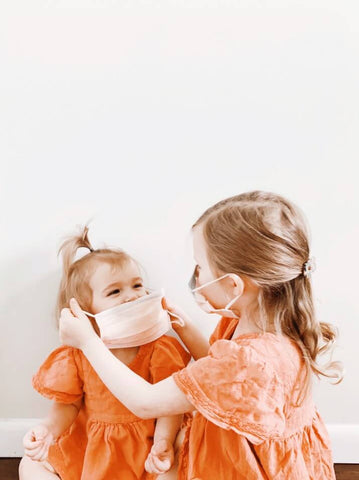 two young children putting on face mask