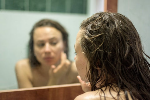 Girl applying skincare in mirror