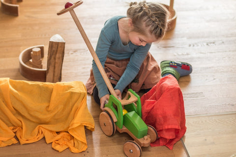 Mädchen spielt mit lenkbaren Holztraktor MIO