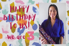 Lady stands with two bolts of fabric next to text that reads "Happy Birthday to us! We turn 3!"