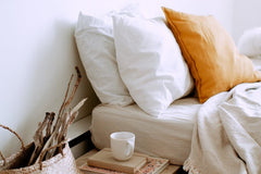 Fluffy pillows on bed, with books on bedside table