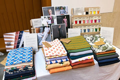 Table stall with folded pieces of fabrics, sewing patterns and sewing threads