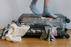 Feet standing on luggage with clothes overspill