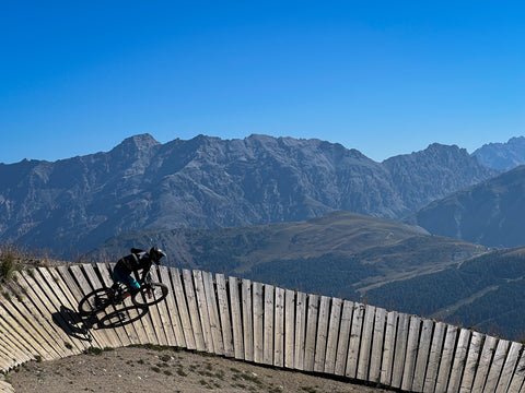 Livigno Mottolino Bikepark Mountainbiker fährt Wallride im Hintergrund schönes Panorma