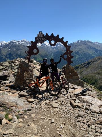 Bikepark Bikerepublic Sölden Mountainbiker stehen vor Stahlbogen mit Bergpanorama