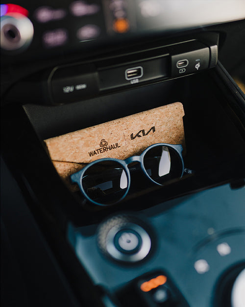 Navy waterhaul sunglasses with cork sunglasses case on the dashboard of a kia car