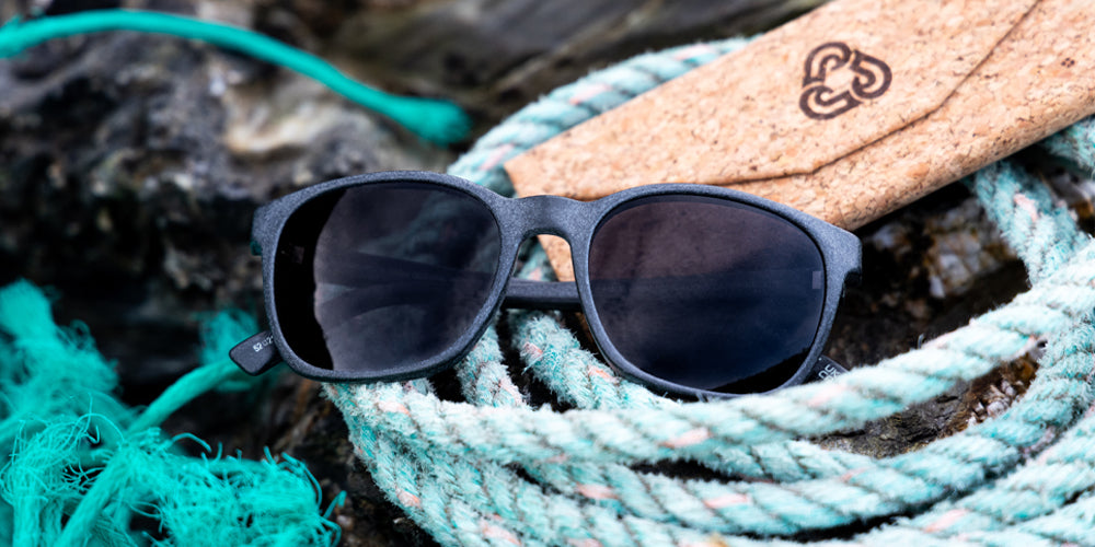 Grey sunglasses on a blue rope with a cork glasses case