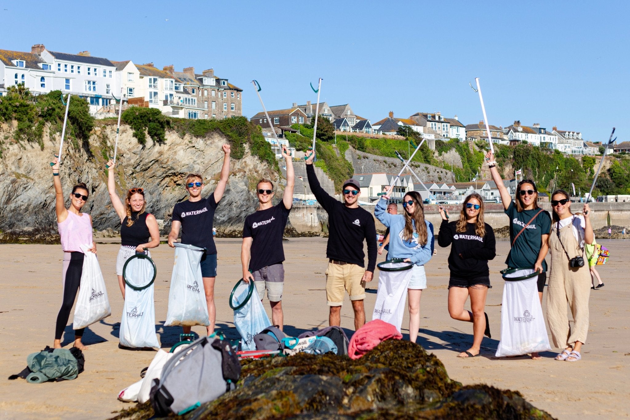 beach cleaning group on beach holding recycled litter pickers in the air