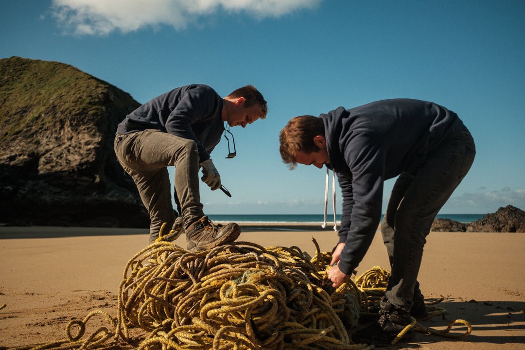 People collecting washed up fishing ropes on a beach