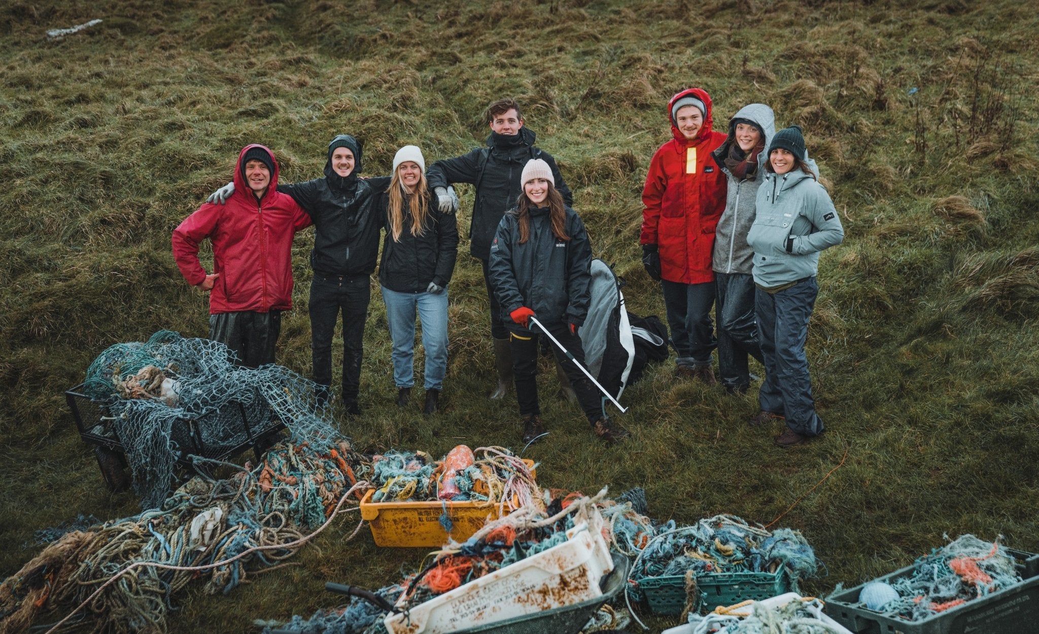 group of people stood on grassy hill with marine litter and rubbish collected from the beach