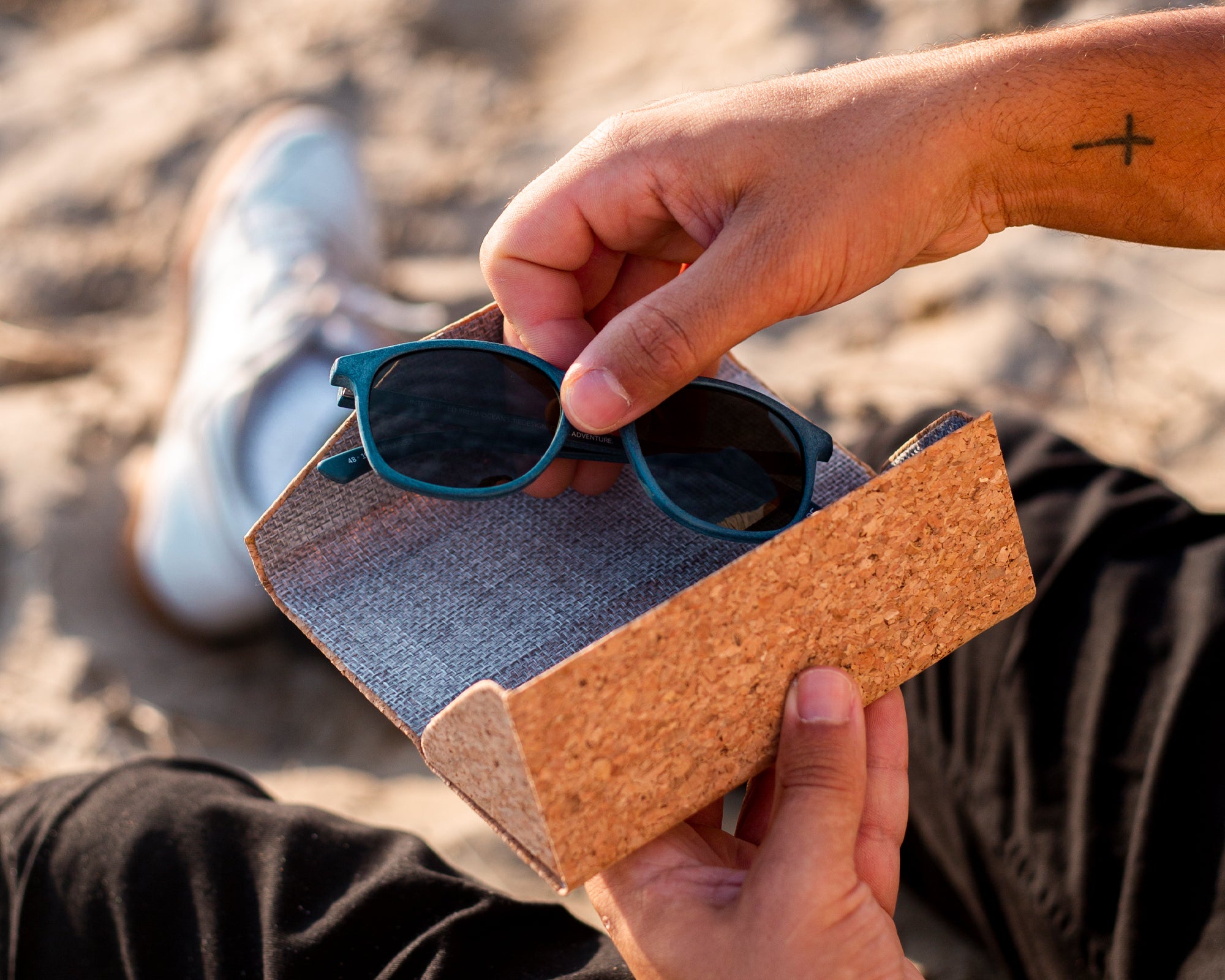 hand picking up waterhaul kynance navy recycled sunglasses out of cork folding sunglasses case