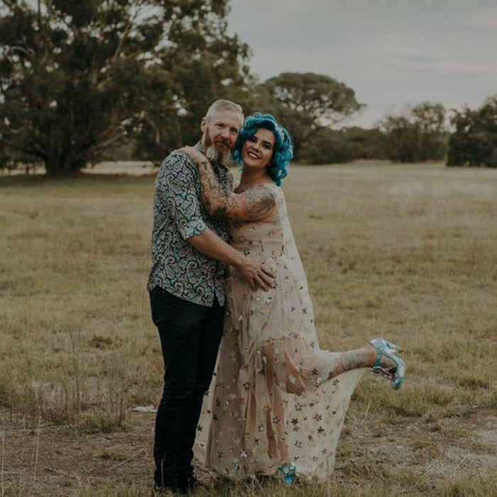 Keeley and her husband embracing in a field, smiling at the camera