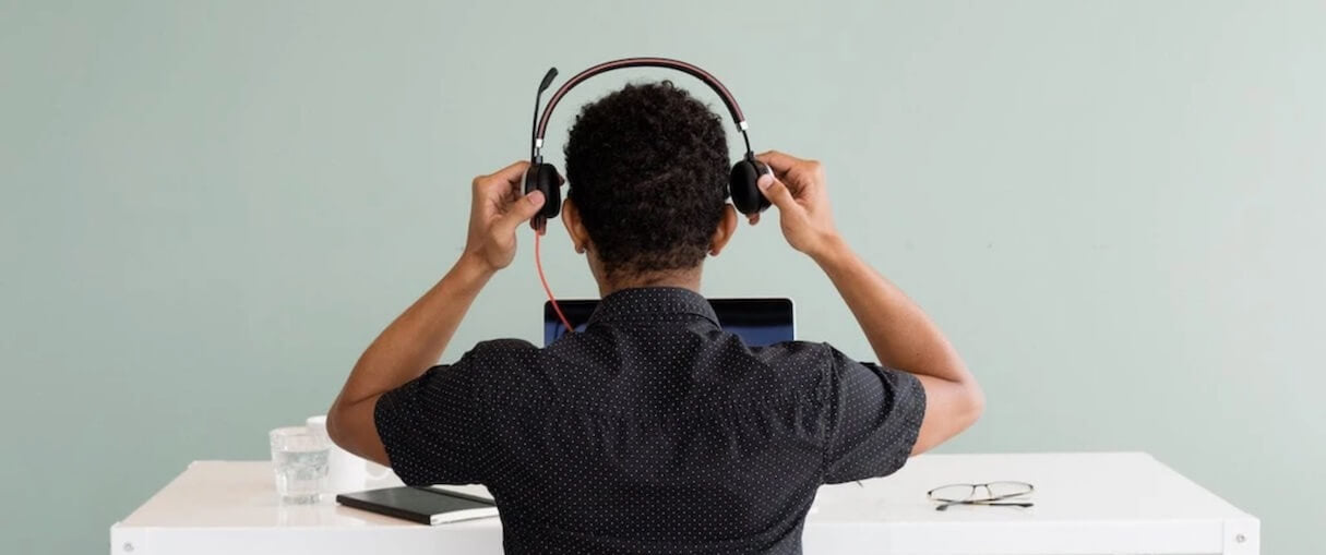 App customer service: Photo of a man putting a headset on while sitting at a computer.