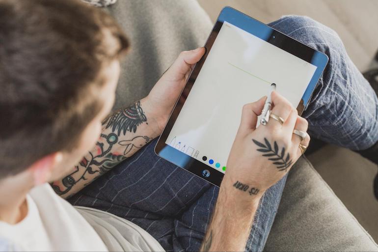 man sitting with a stylus and ipad in his lap