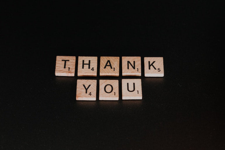 Reply to review: The words "thank you" are spelled out using Scrabble tiles, laid out on a black background.