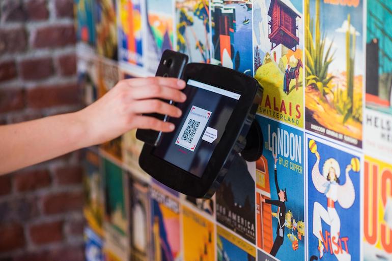 unboxing: phone scanning a QR code off of a tablet fastened to a wall of graffiti 