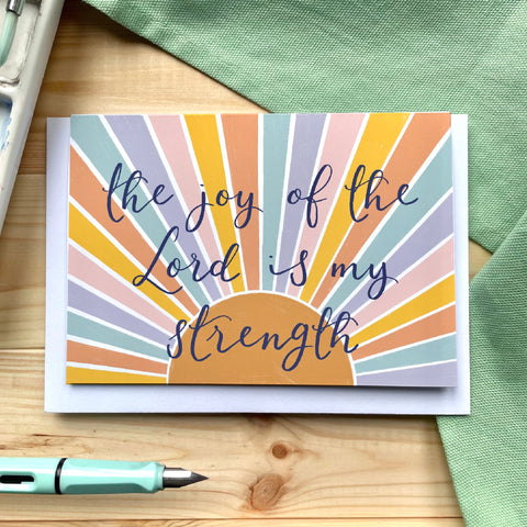 Different baptism card with the words “the joy of the Lord is my strength” hand lettered on bright colours